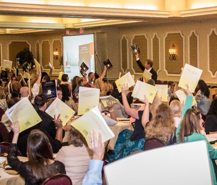 Teachers holding their Time To Teach resource manuals in the air